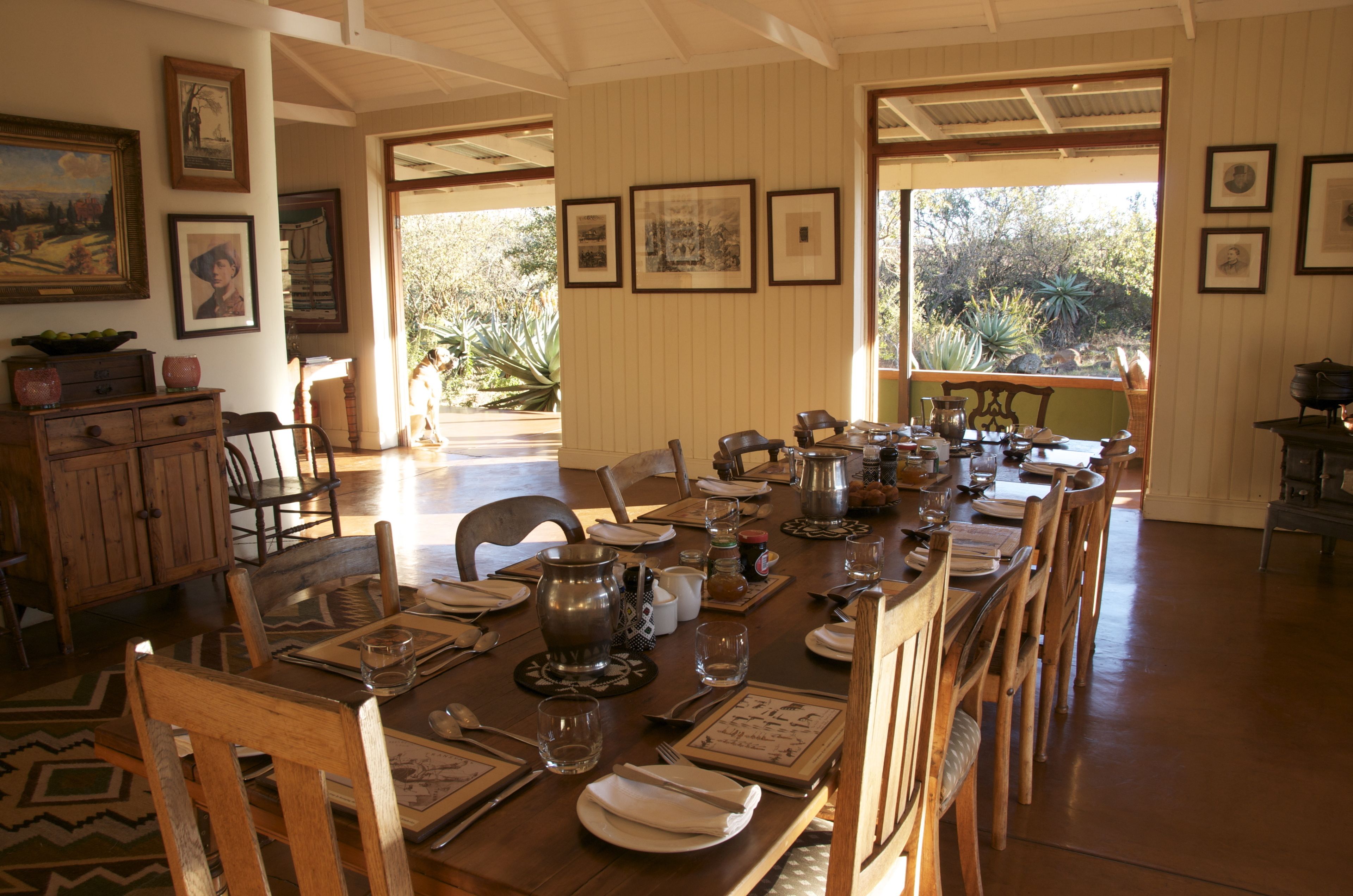 Comedor con una larga mesa dispuesta para una comida, rodeada de sillas de madera.