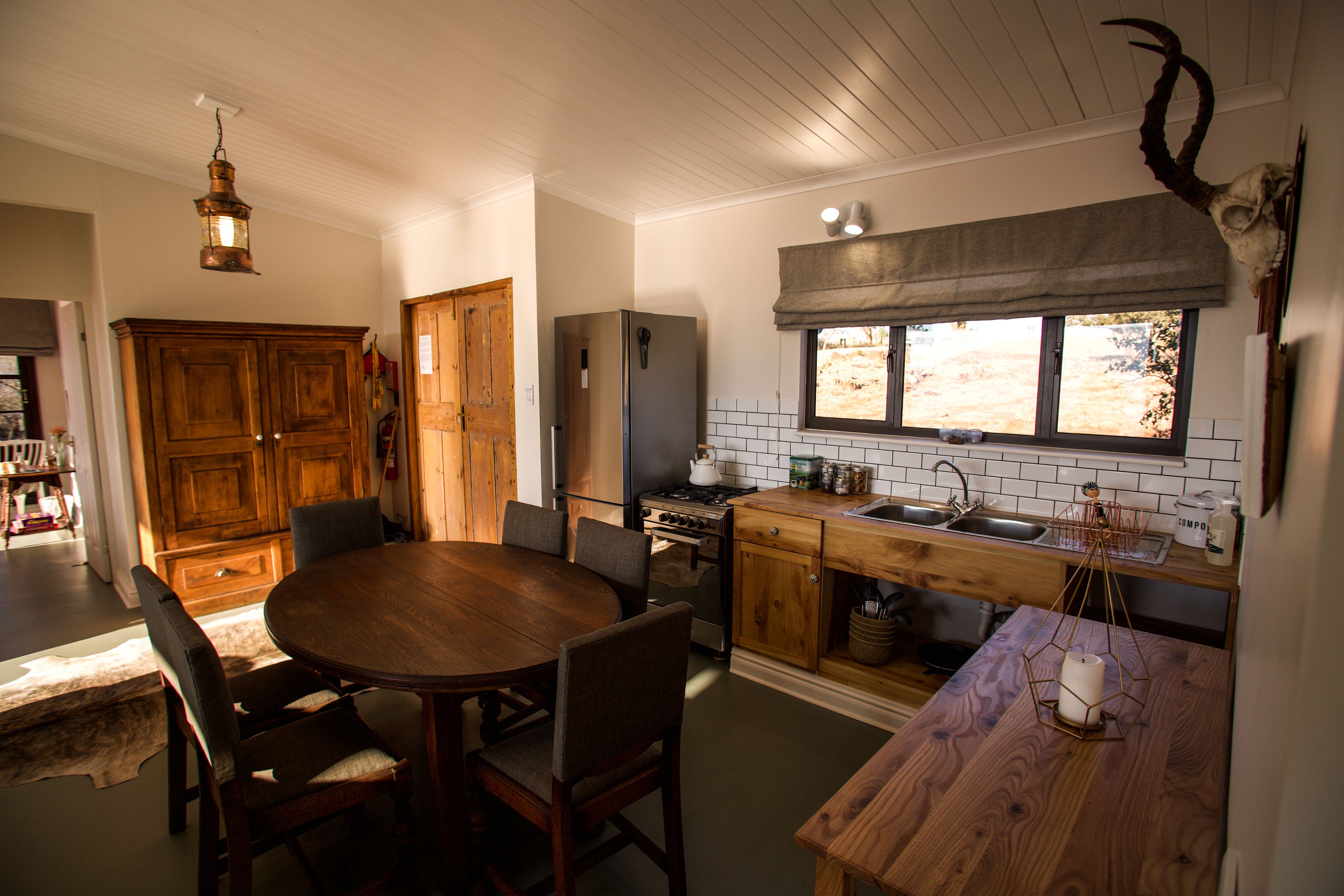 A kitchen with wooden cabinets, a dining table, and a window with a view.