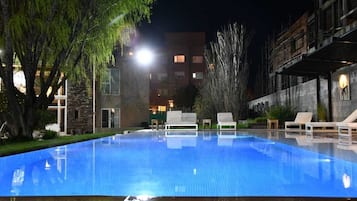 Una piscina al aire libre de temporada, sillones reclinables de piscina