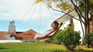 A hammock in a grassy area with a building in the background.