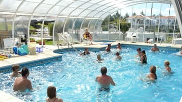 Una piscina techada, una piscina al aire libre, sombrillas