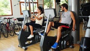 Two people using treadmills in a gym with bicycles in the background.