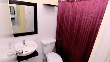 Une salle de bain avec un lavabo blanc, des toilettes et un rideau de douche rouge.