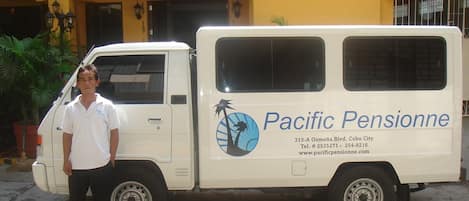 A white van with "Pacific Pensionne" branding parked in front of a building.
