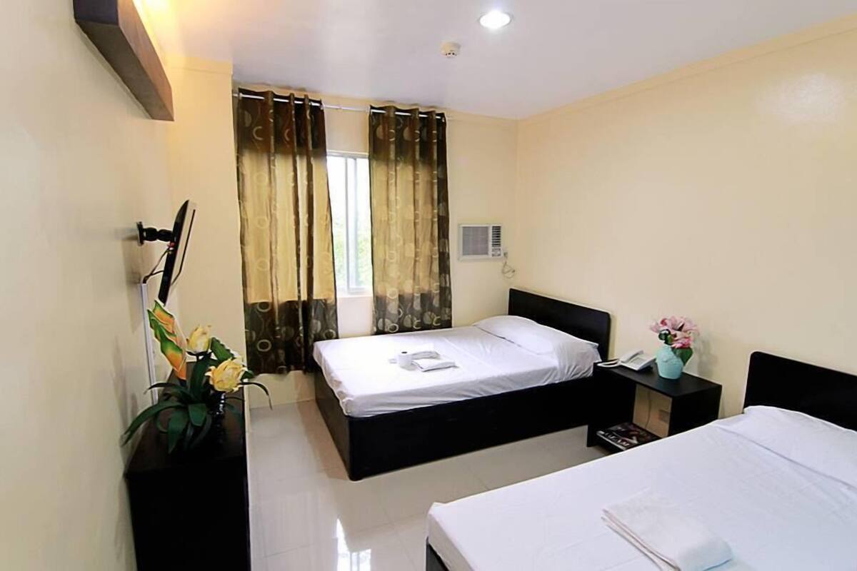 Una habitación de hotel con cama, mesita de noche y velador.