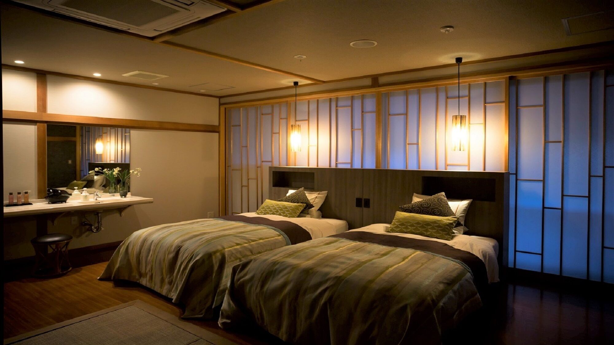 A hotel room with two beds, a bedside table, a mirror, and a wall with vertical panels.