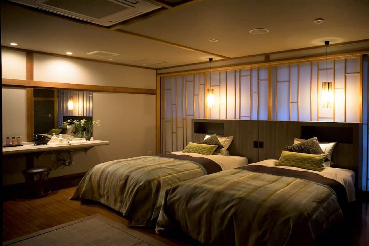 A hotel room with two beds, a bedside table, a mirror, and a wall with vertical panels.