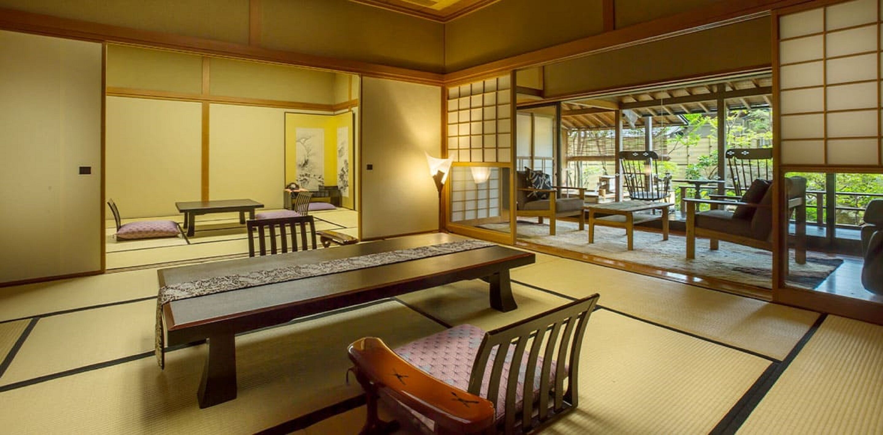 Une pièce de style japonais traditionnel, avec un sol recouvert de tatamis, une table basse et un espace détente agrémenté de coussins.