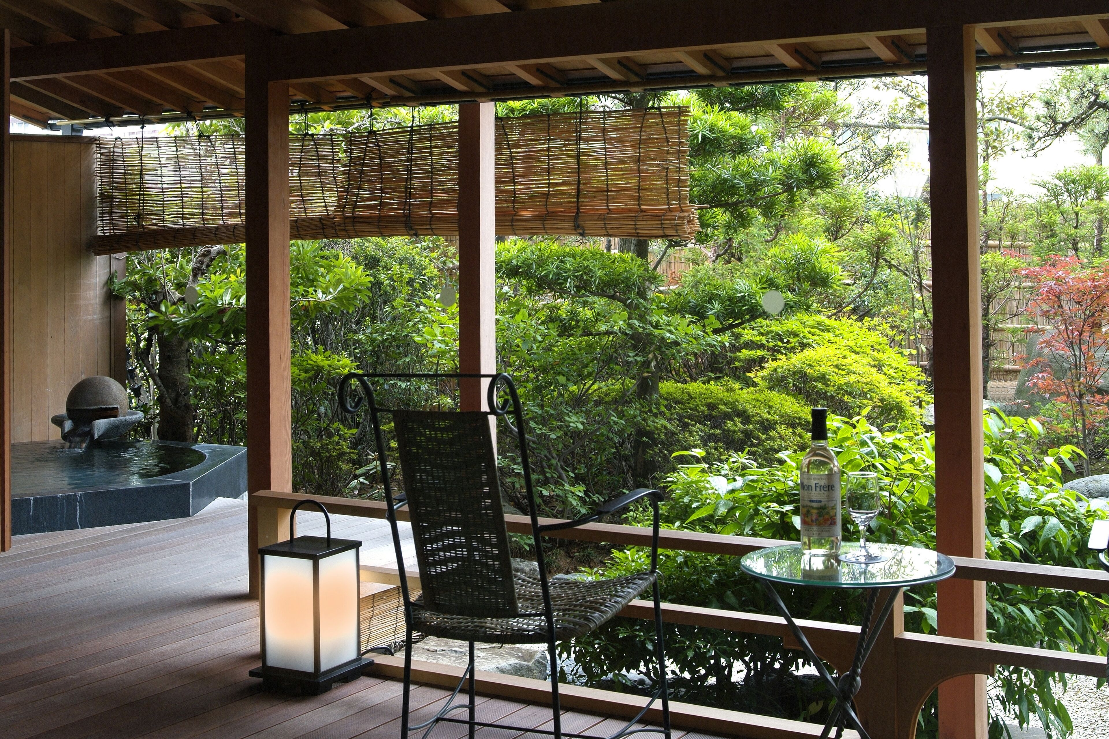 A covered outdoor seating area with a chair, table, and lantern.