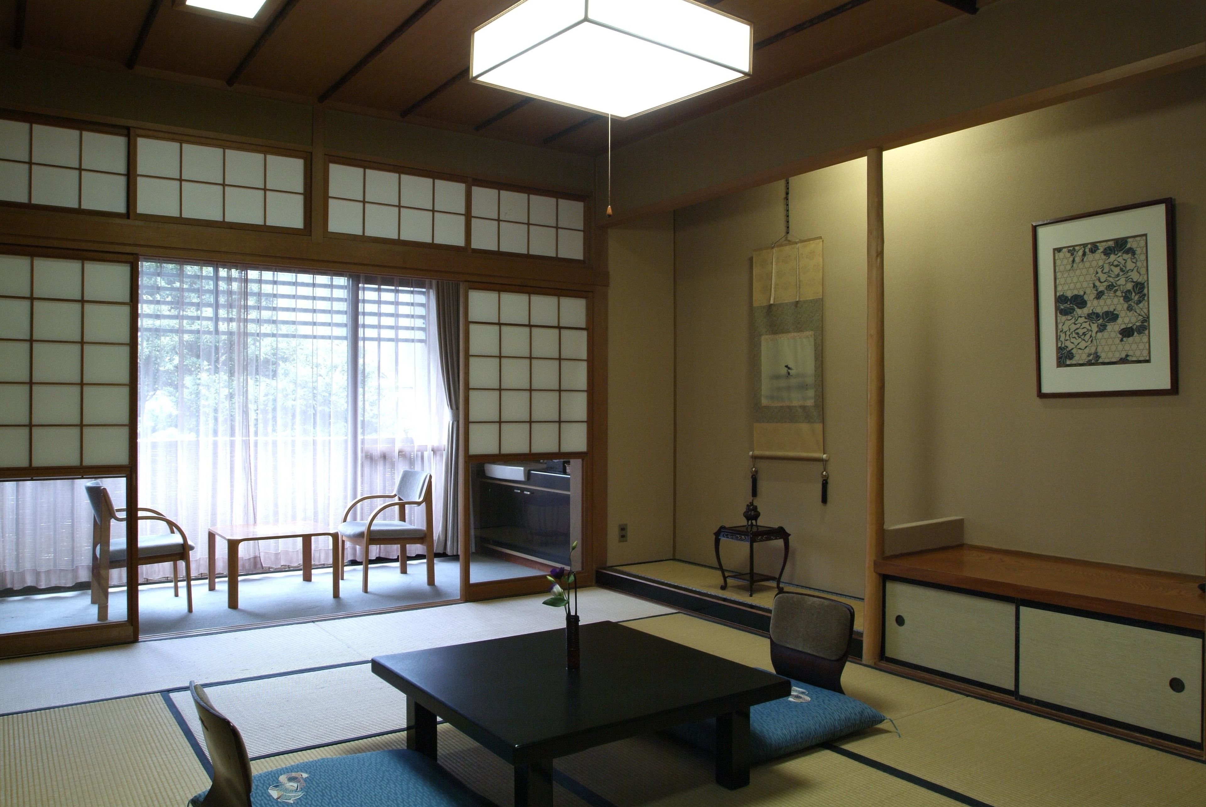 Una habitación japonesa tradicional con suelo de tatami, una mesa baja y puertas correderas.