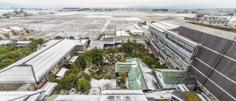 An aerial view of a large industrial area with multiple buildings, including a modern structure with a green roof and a traditional building with a tiled roof.