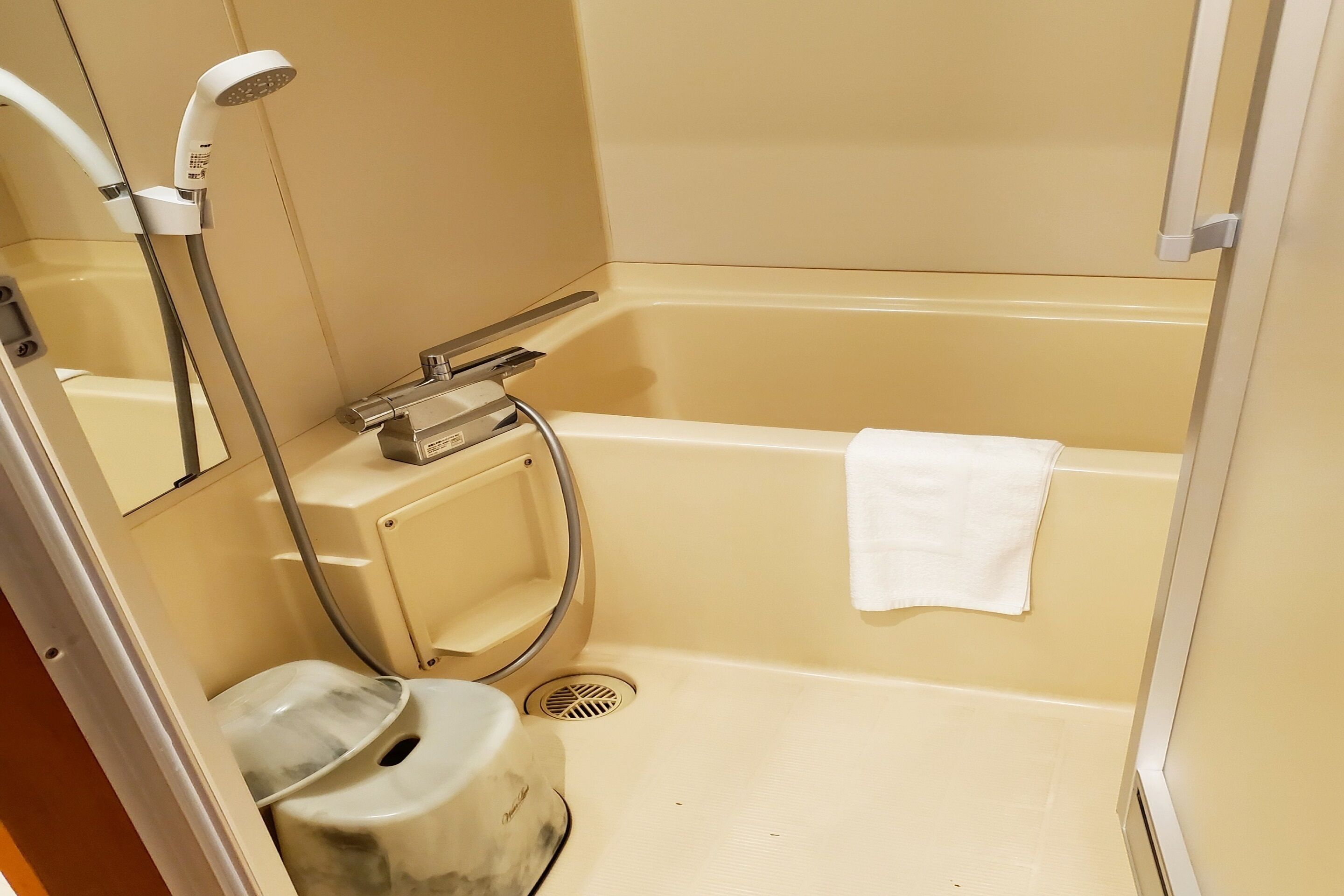 Een kleine, praktische badkamer met een bad, toilet en douchekop.