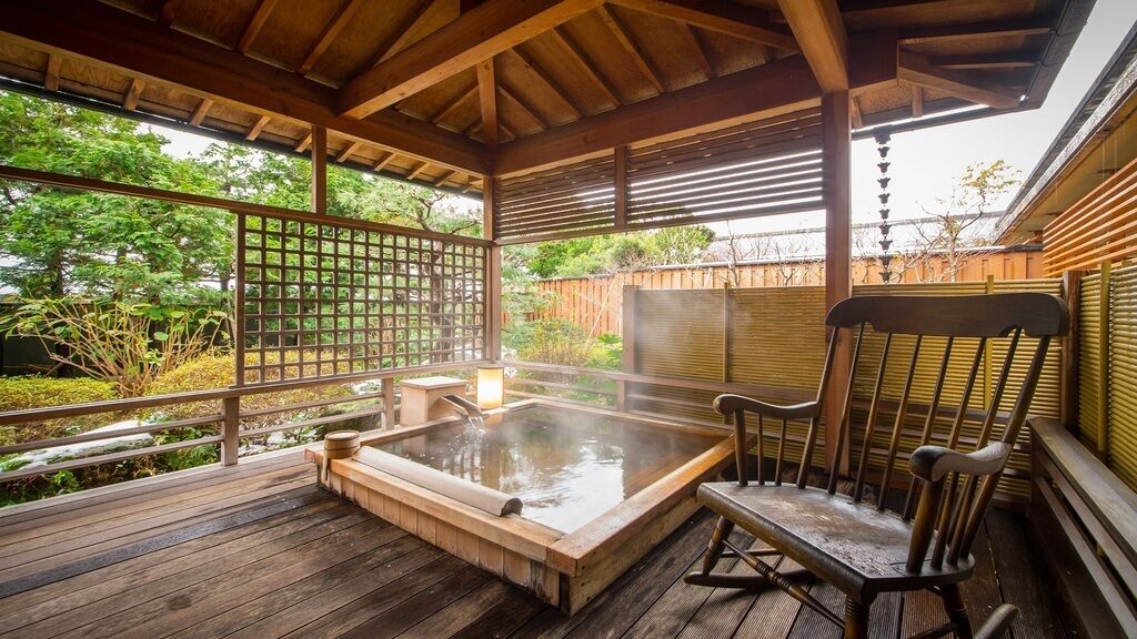 A wooden deck with a hot tub, a wooden chair, and a wooden fence.