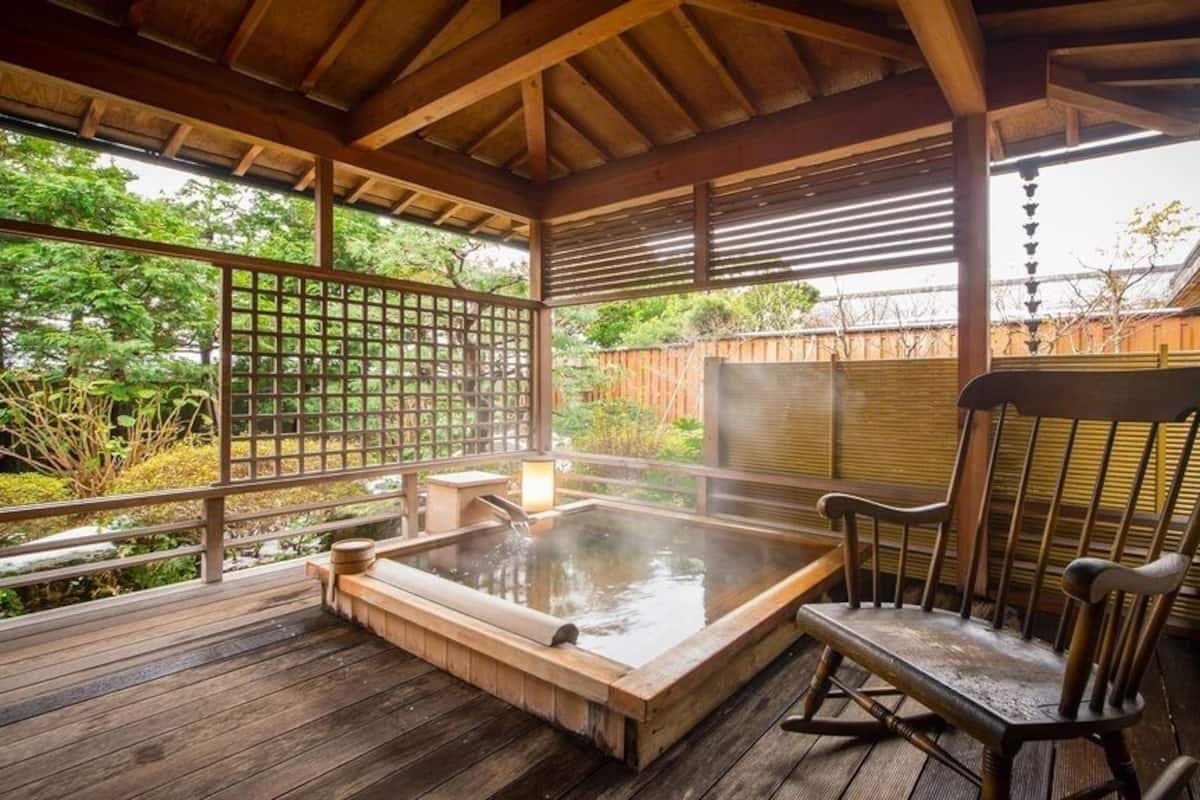 A wooden deck with a hot tub, a wooden chair, and a wooden fence.