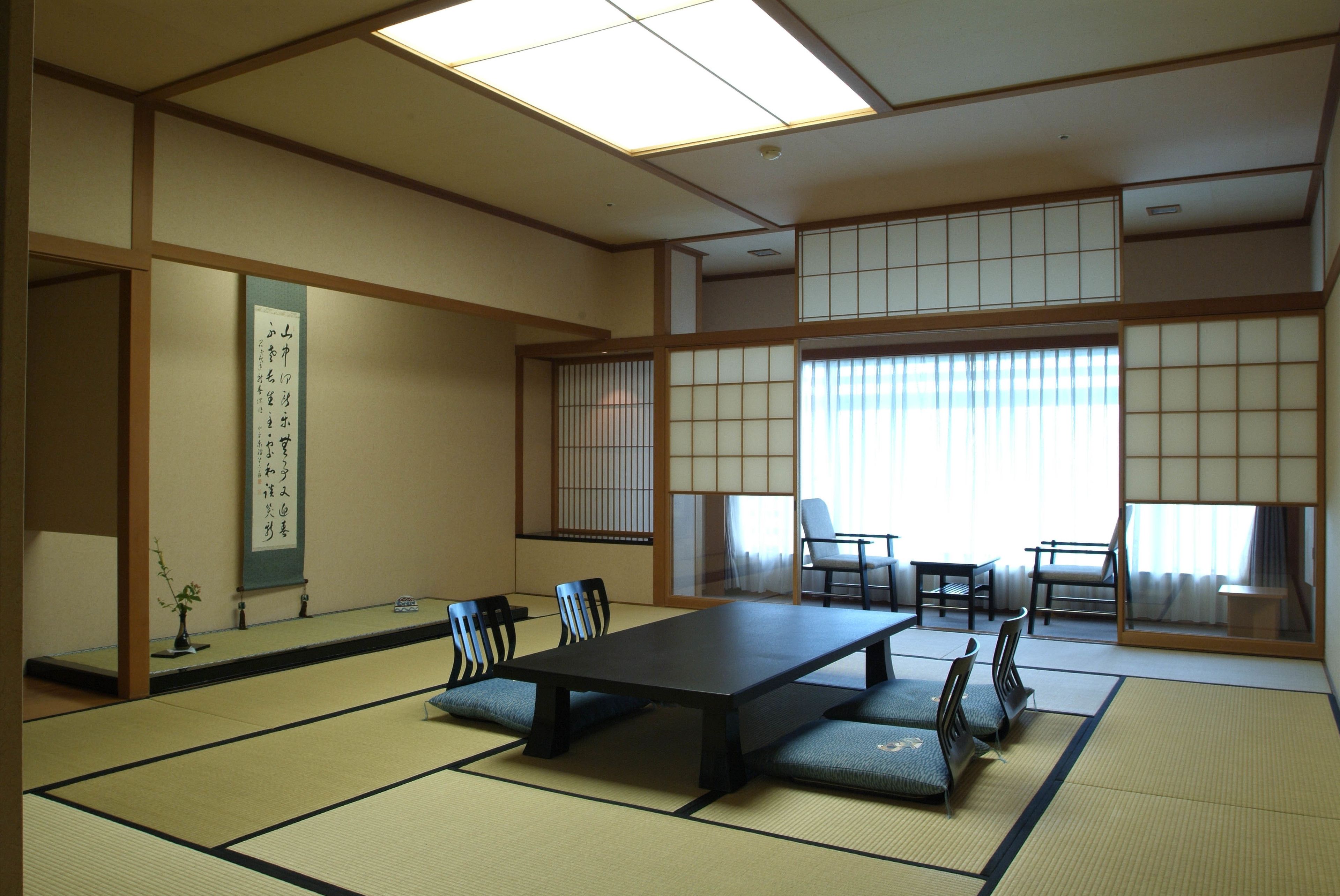 Ein traditioneller japanischer Raum mit Tatami-Boden, einem niedrigen Tisch und mehreren Stühlen.