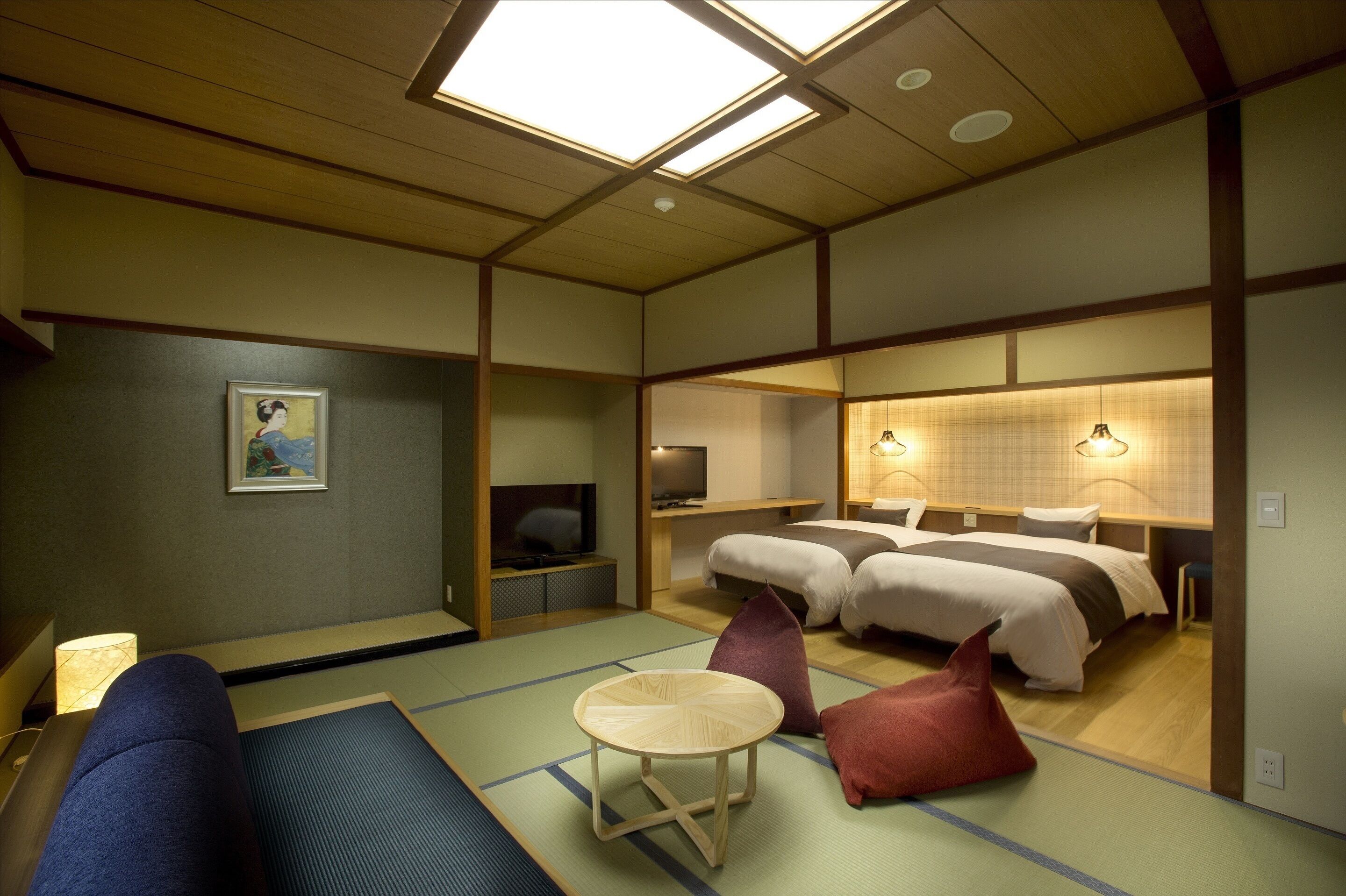 Una habitación tradicional japonesa con suelo de tatami, futón, televisión y una pequeña mesa.
