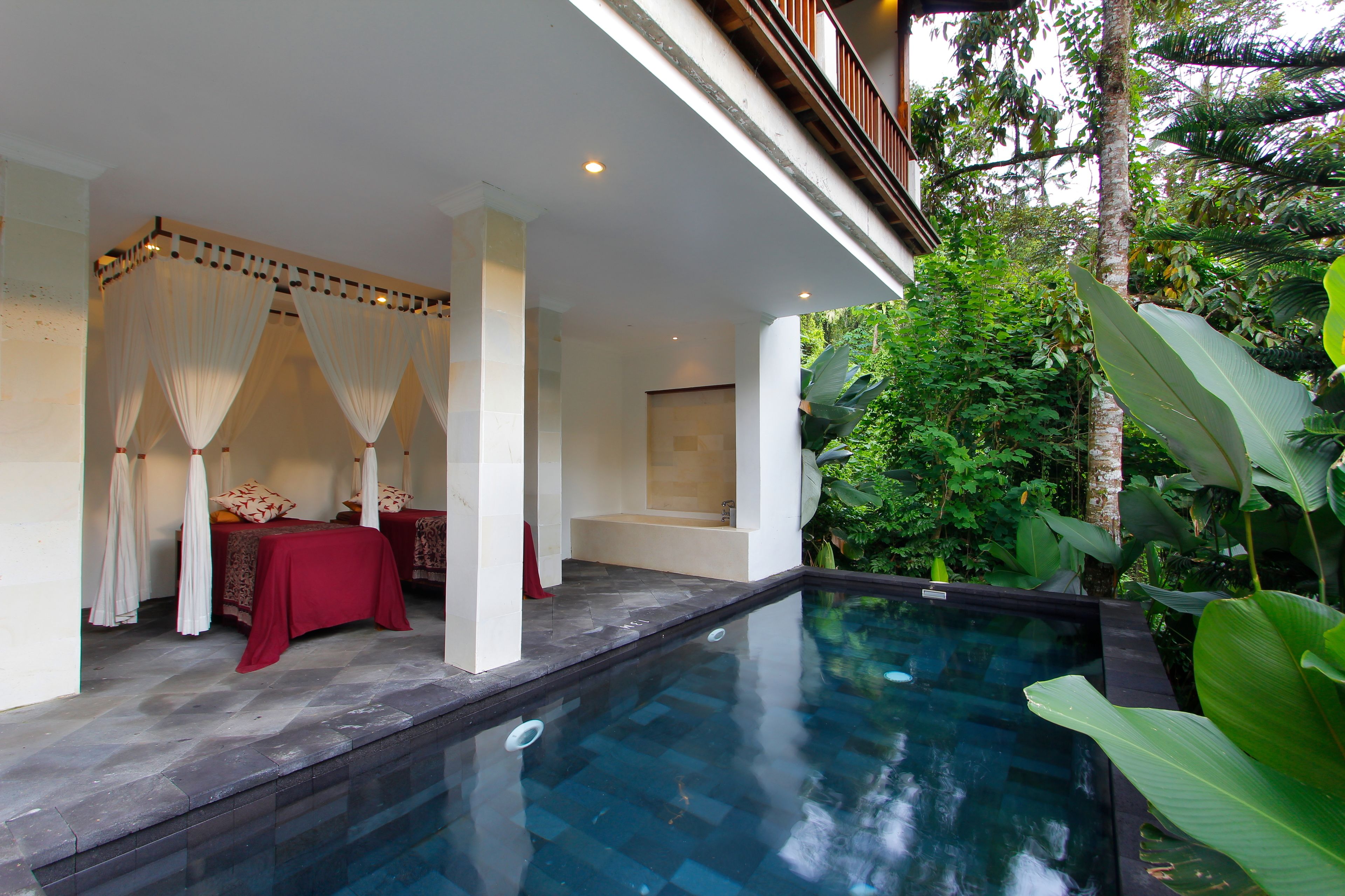 Un área de spa con piscina, dos camillas de masaje y una pérgola.