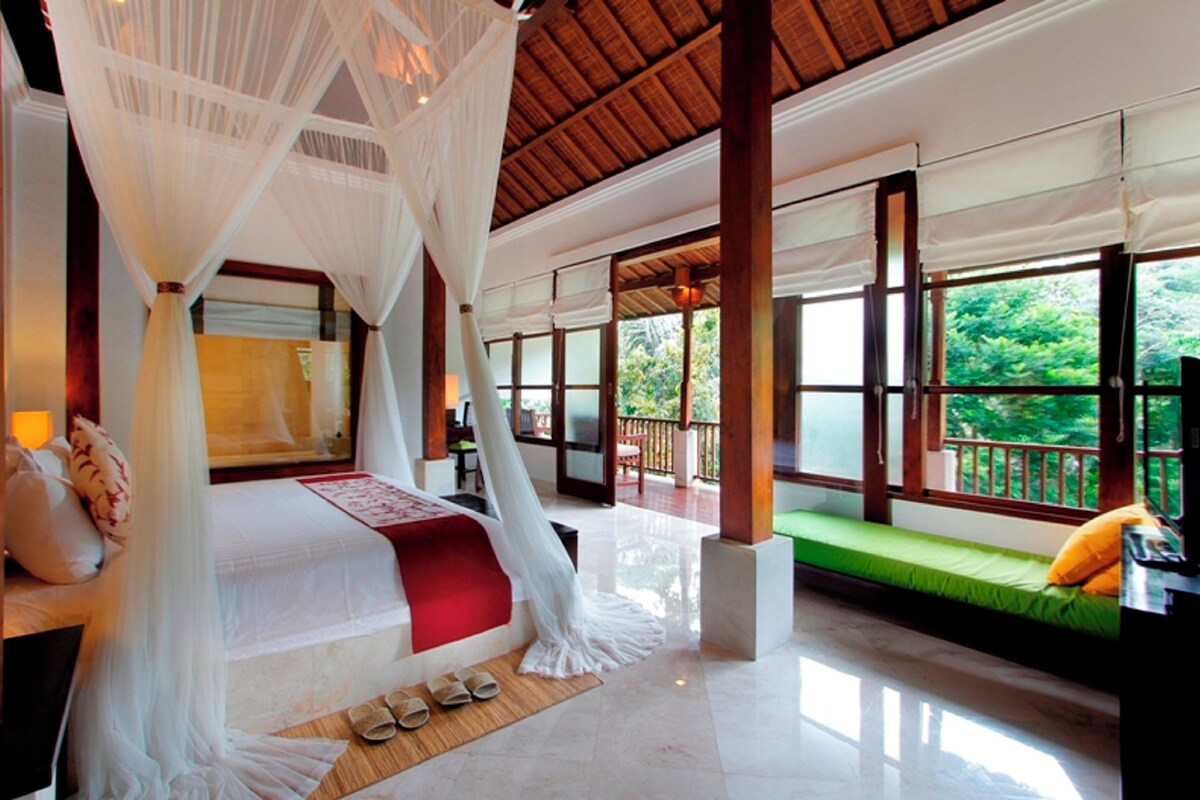 Une chambre spacieuse avec un grand lit, un balcon et une vue sur la verdure.