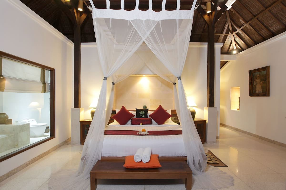 Un dormitorio con cama con dosel, una mesita de noche y un ventanal.