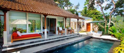 Una casa moderna con piscina, un patio cubierto y un sofá rojo.