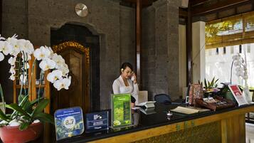 A reception desk with a receptionist, a clock, and a potted orchid.