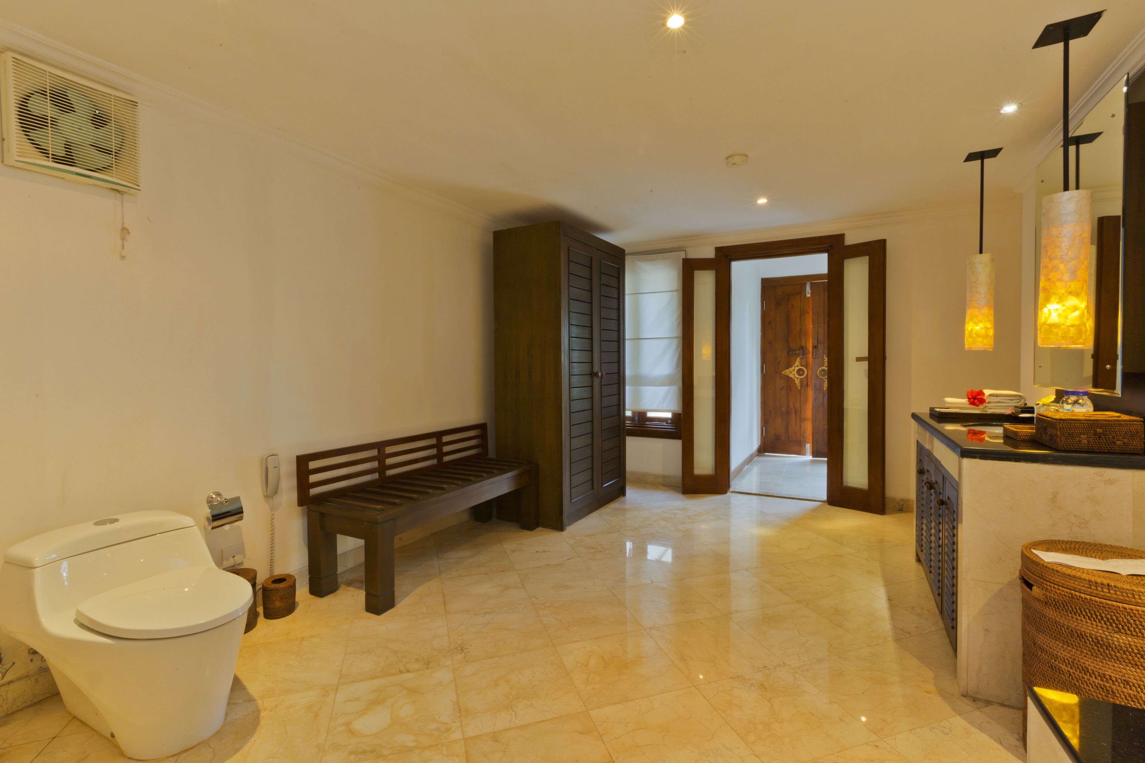 Une salle de bain avec des toilettes, un banc et un meuble.