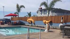 A pool area with a wooden deck, lounge chairs, and a wooden fence.