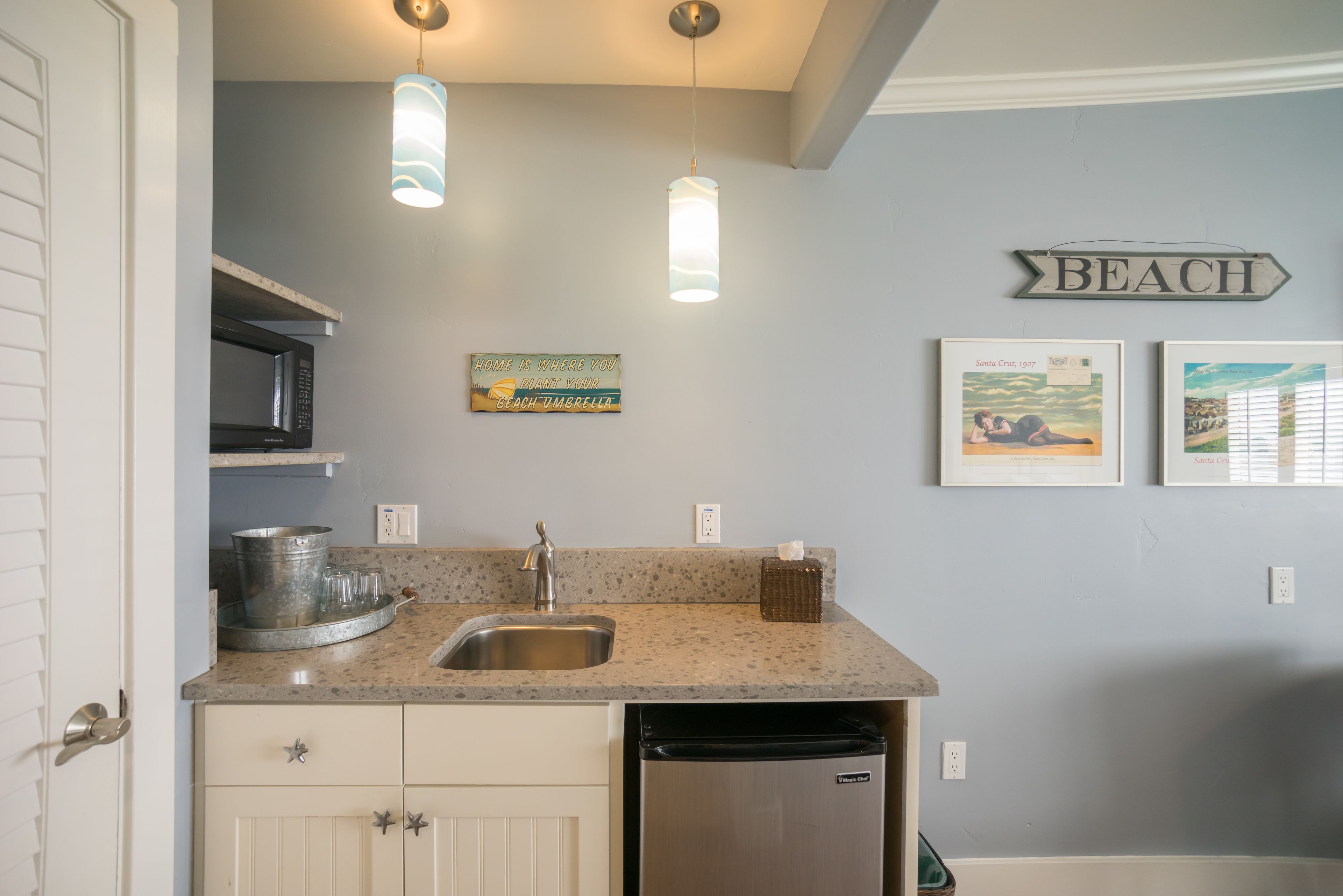 A kitchen with granite countertops, stainless steel appliances, and a 'BEACH' sign on the wall.