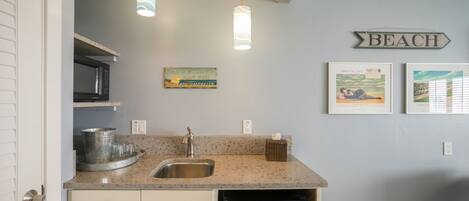 A kitchen with granite countertops, stainless steel appliances, and a 'BEACH' sign on the wall.