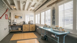 A kitchen with a blue counter, wooden cabinets, and a large window with blinds.