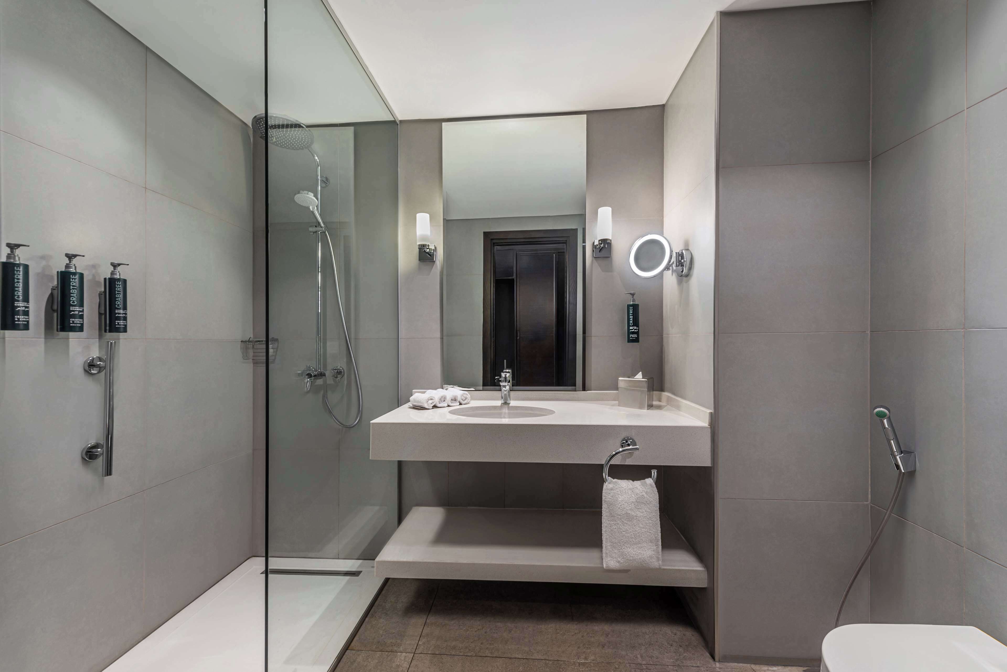 A modern bathroom with a glass-enclosed shower, a white sink, and a toilet.