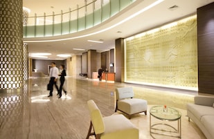 A modern lobby with a reception desk, seating area, and decorative wall panels.