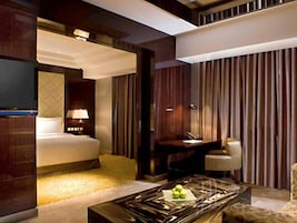 A modern hotel room with a bed, a desk, a chair, and a coffee table.