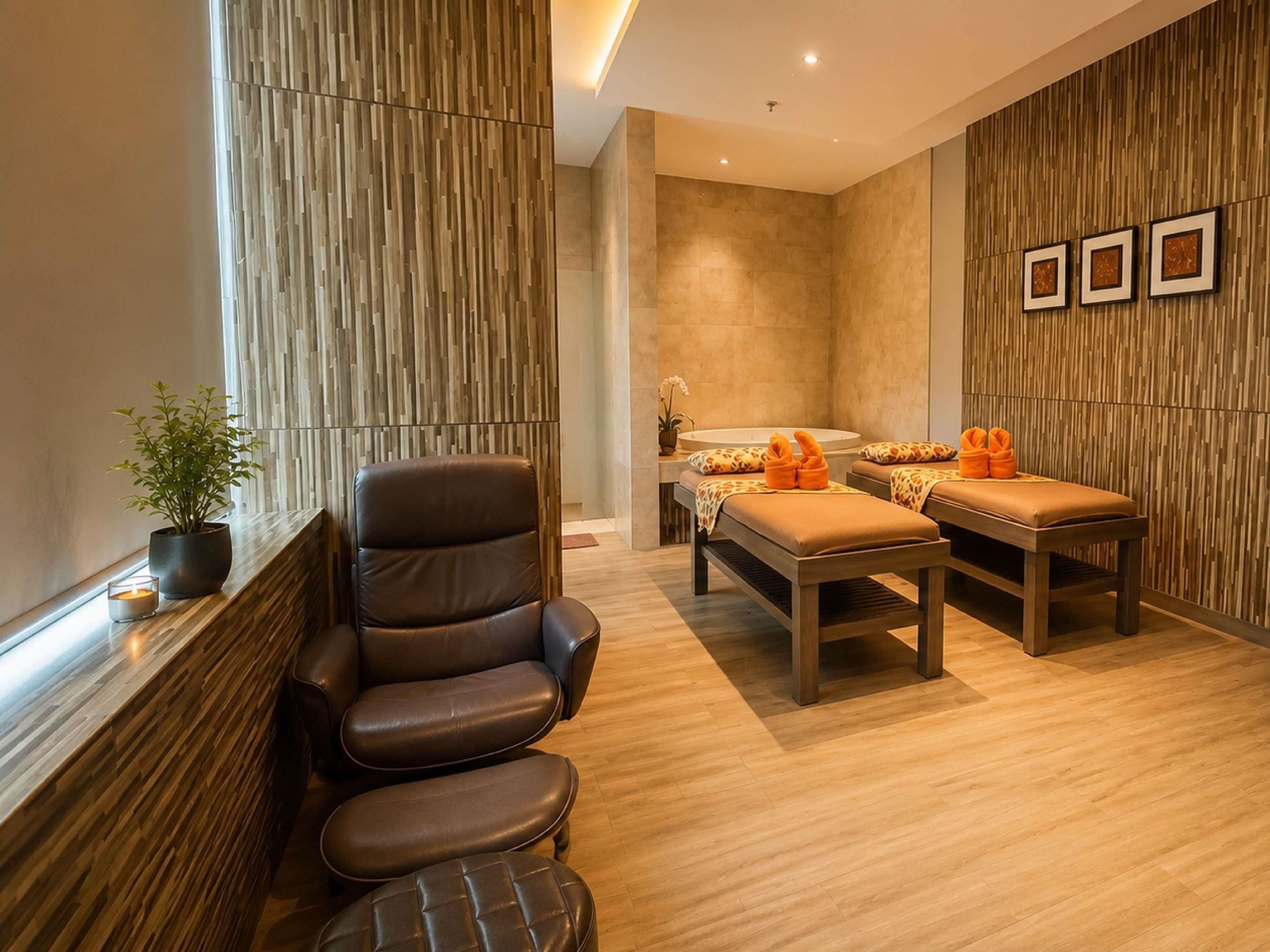 A spa room with a massage table, a massage chair, and a small table with a plant.