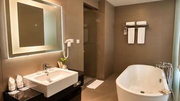 A modern bathroom with a large bathtub, a vanity with a mirror, and a shower area.