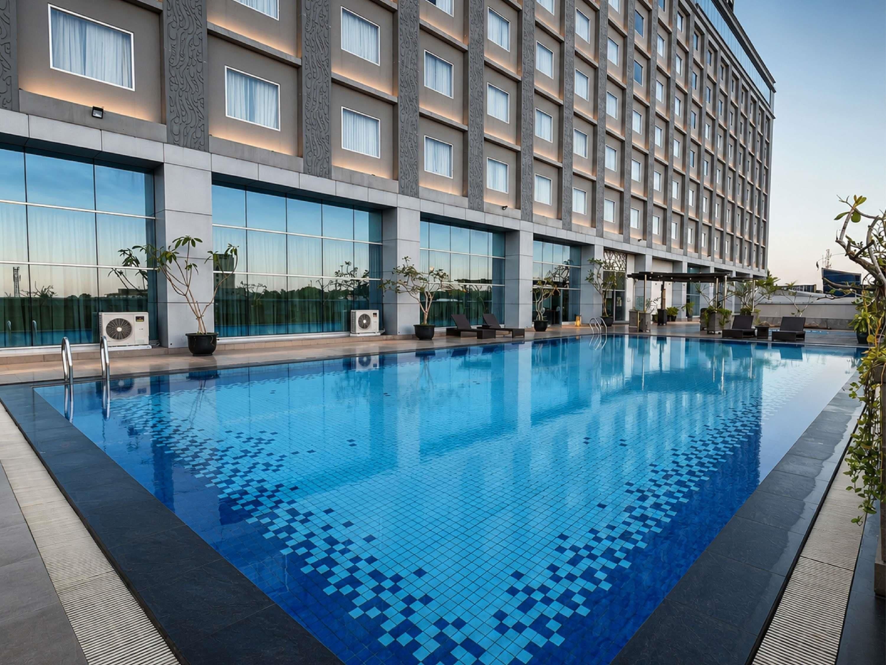 Un hotel con piscina, aire acondicionado y plantas en macetas.