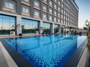 Ein Hotel mit Schwimmbad, Klimaanlagen und Topfpflanzen.