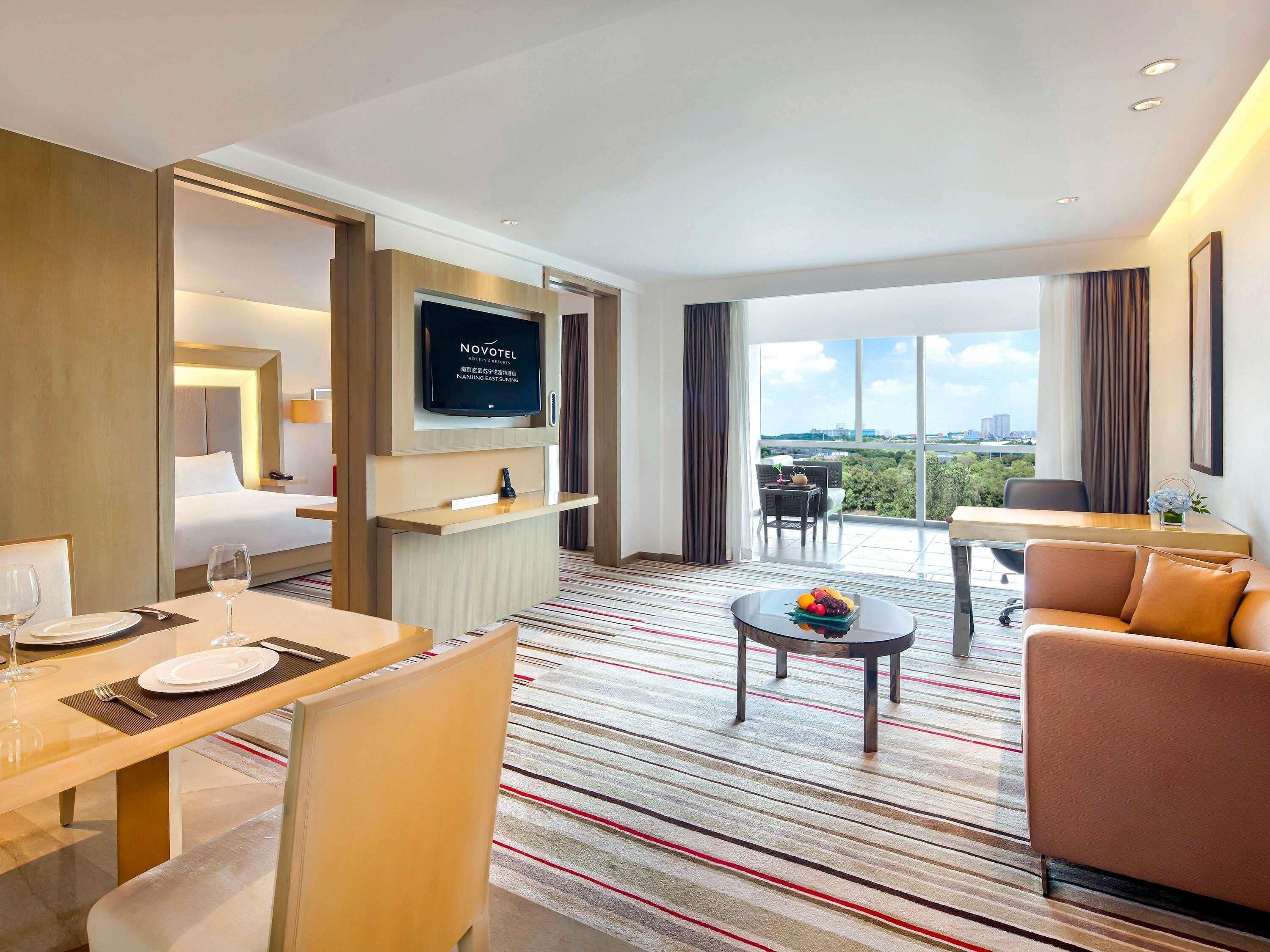 Ein Hotelzimmer mit Bett, Fernseher, Essbereich, Balkon mit Blick und einer Sitzecke.