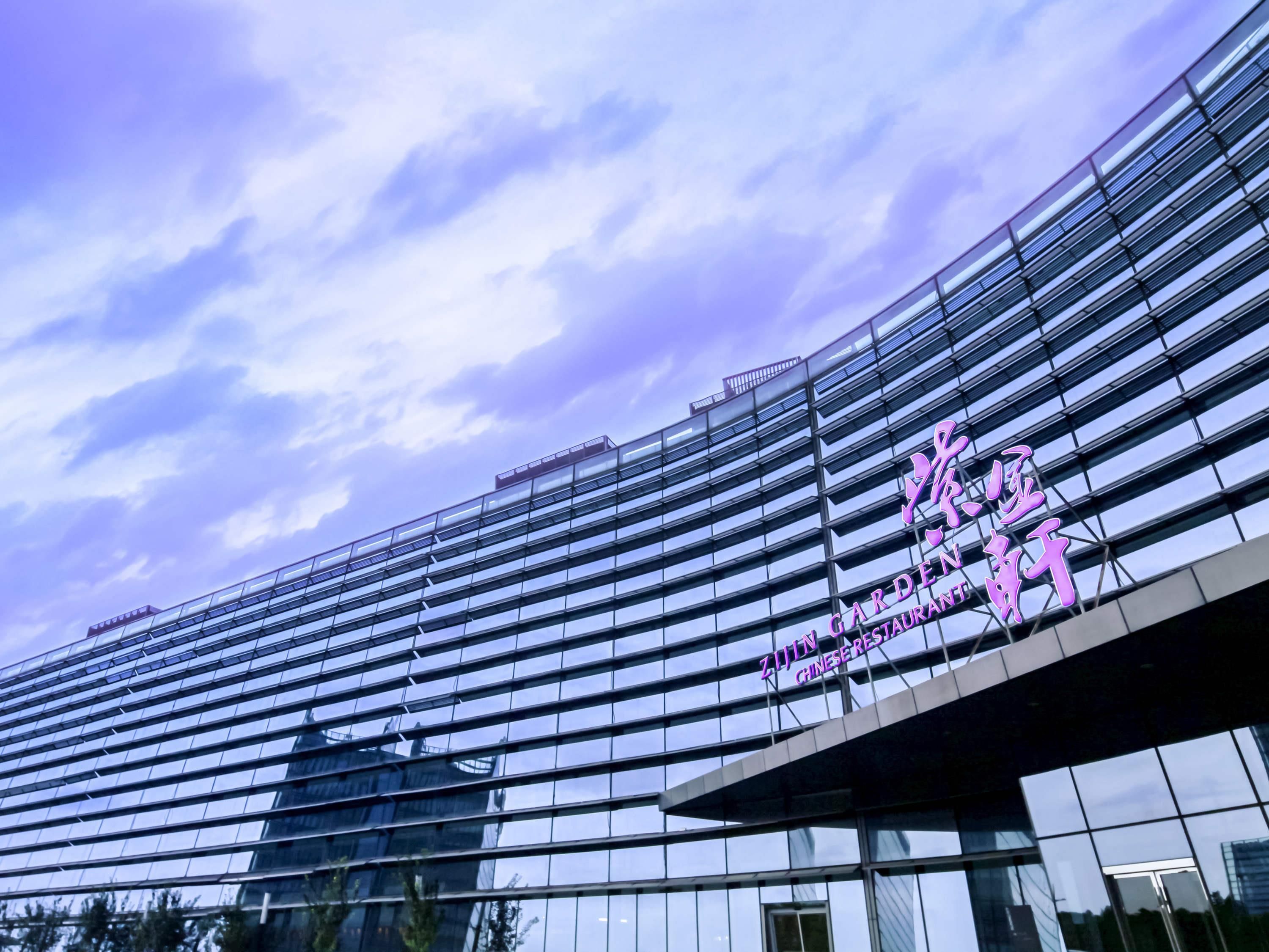 A modern building with a glass facade and a sign that reads "Zijin Garden Restaurant".