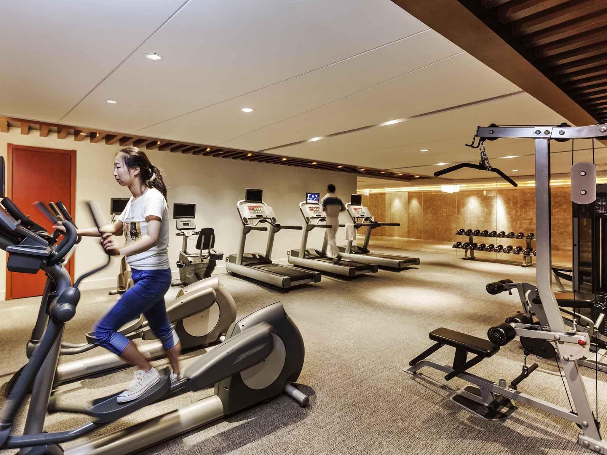 A gym with treadmills, weight machines, and dumbbells.