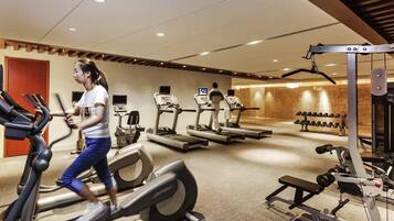 A gym with treadmills, weight machines, and dumbbells.
