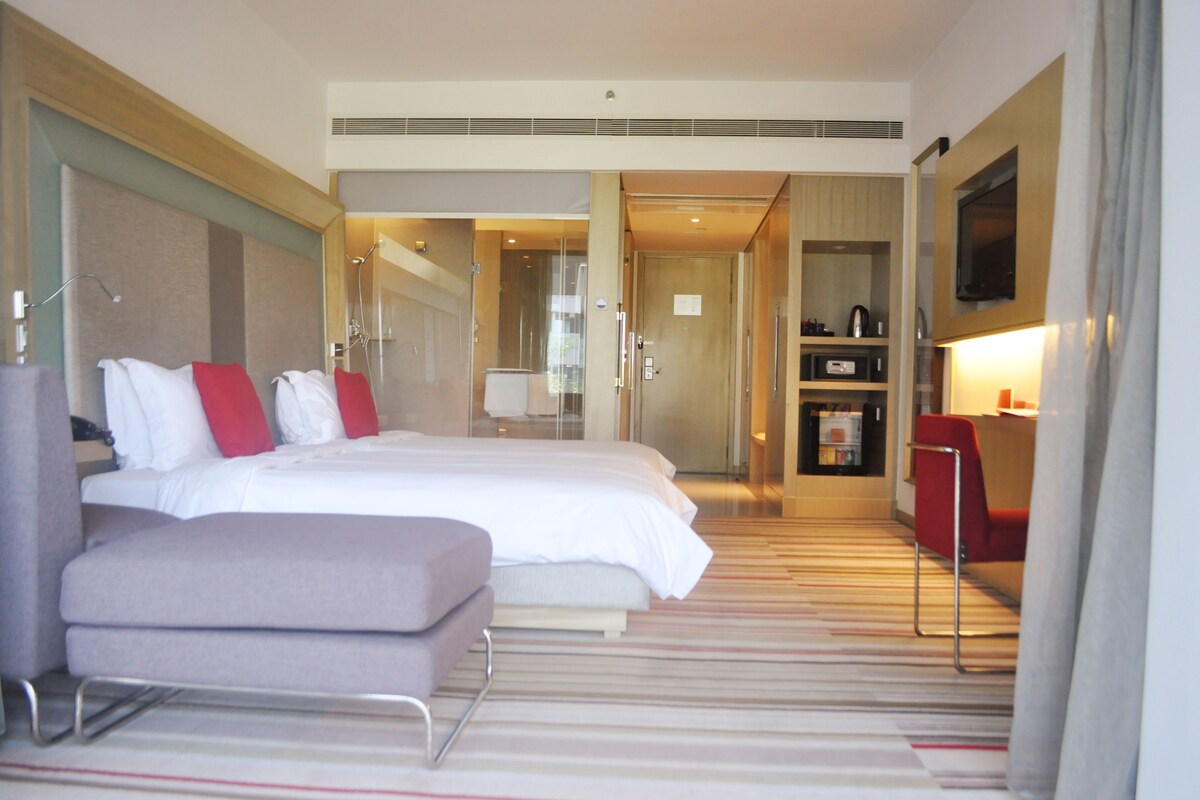 Een hotelkamer met een groot bed, een bureau, een stoel en een televisie.