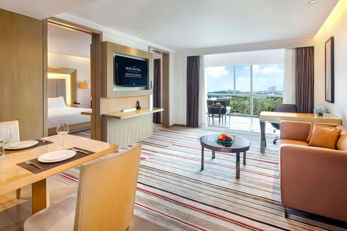 Une chambre d’hôtel comprenant un lit, une télévision, un coin repas, un balcon avec vue et un espace détente.