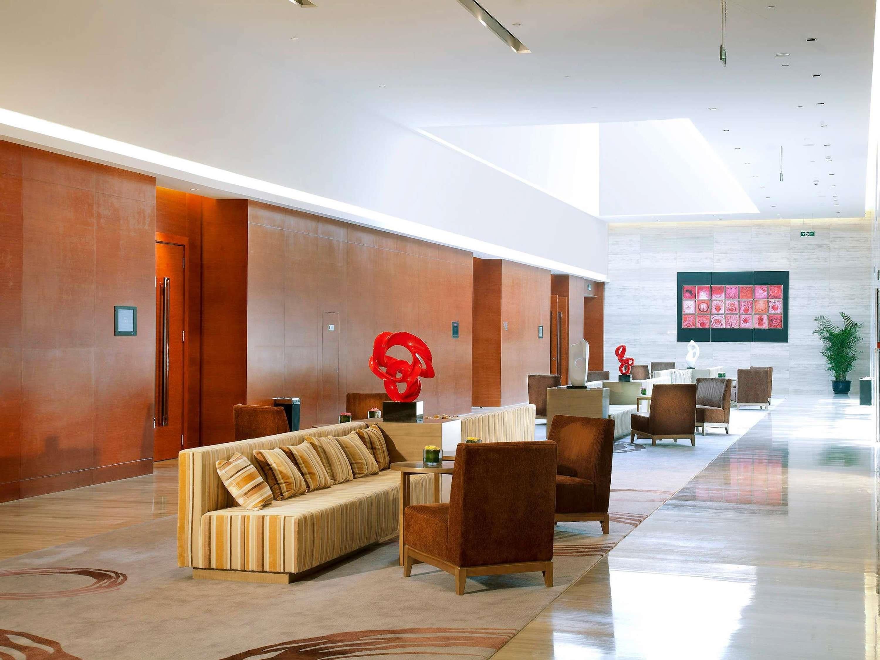 A spacious lobby with a modern design, featuring a sofa, chairs, and a large abstract sculpture.