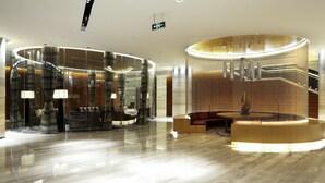 Een moderne lobby met een rond receptiebalie, een trap en een zithoek.