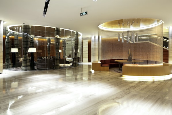 Een moderne lobby met een rond receptiebalie, een trap en een zithoek.