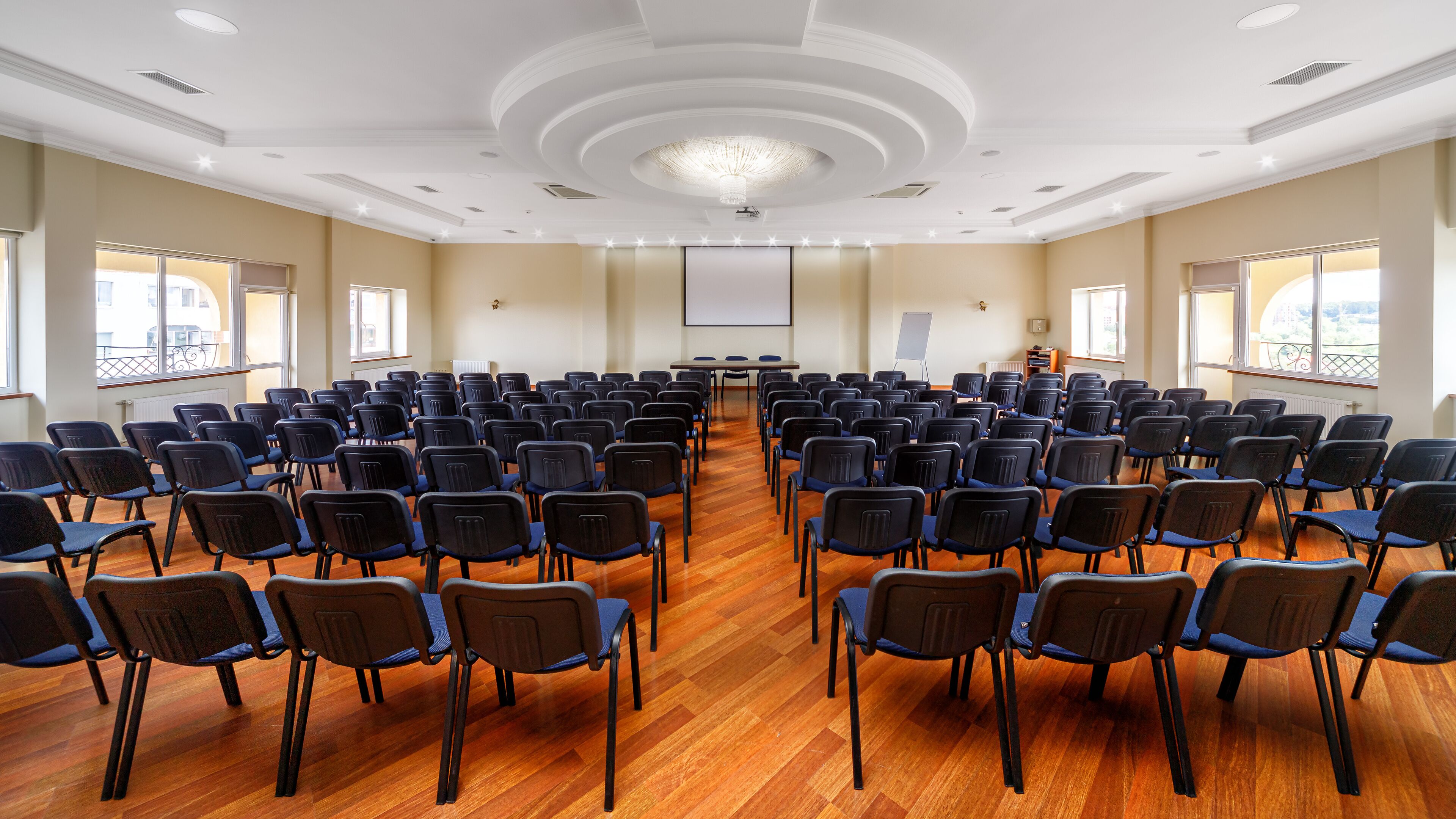 A conference room with rows of chairs, a projector screen, and a whiteboard.