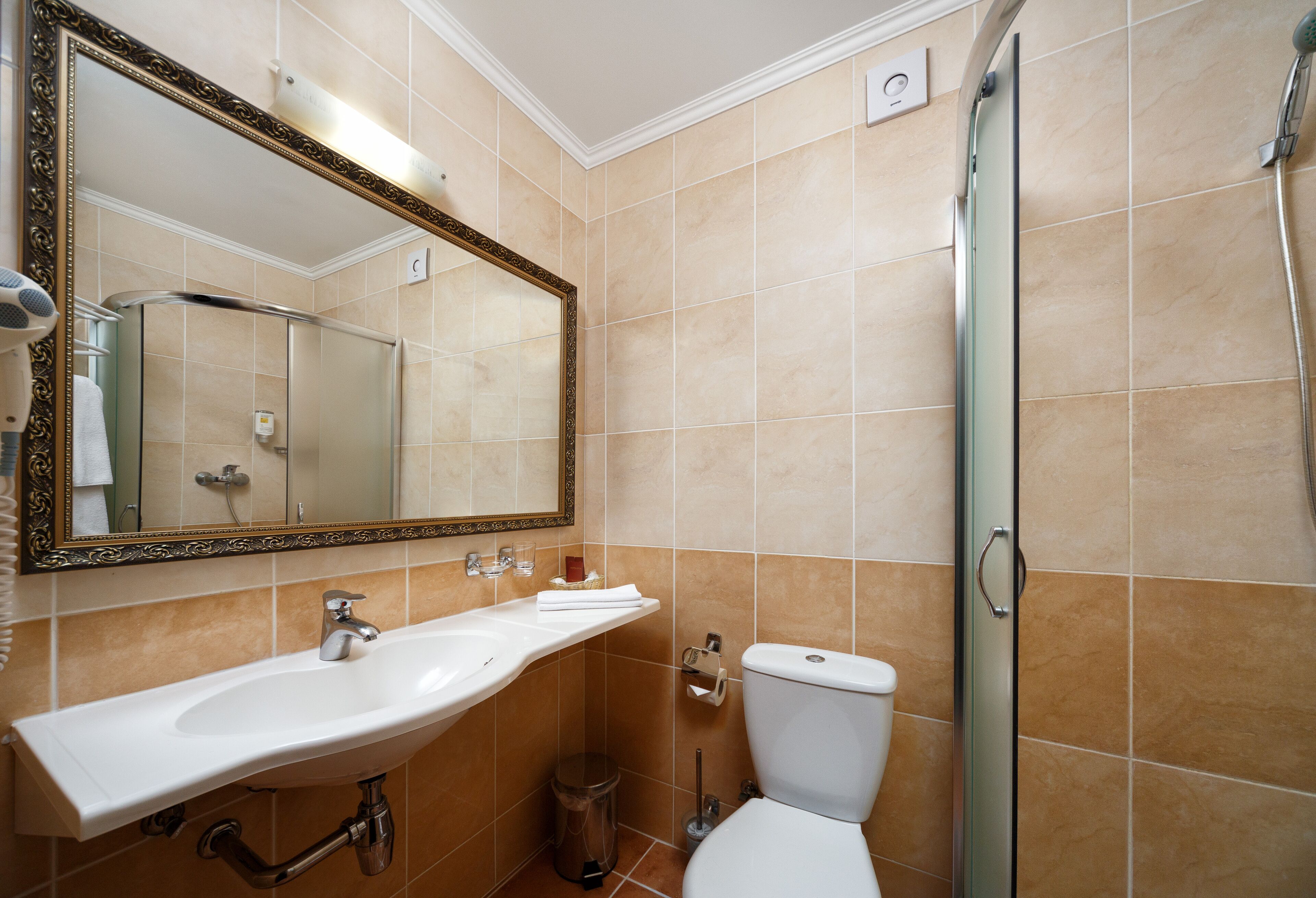A bathroom with a large mirror, sink, toilet, and shower.