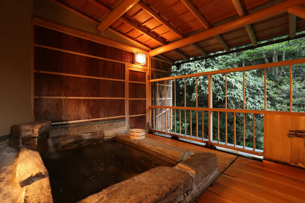 Een traditioneel Japans onsen met houten inrichting en uitzicht op weelderig groen.