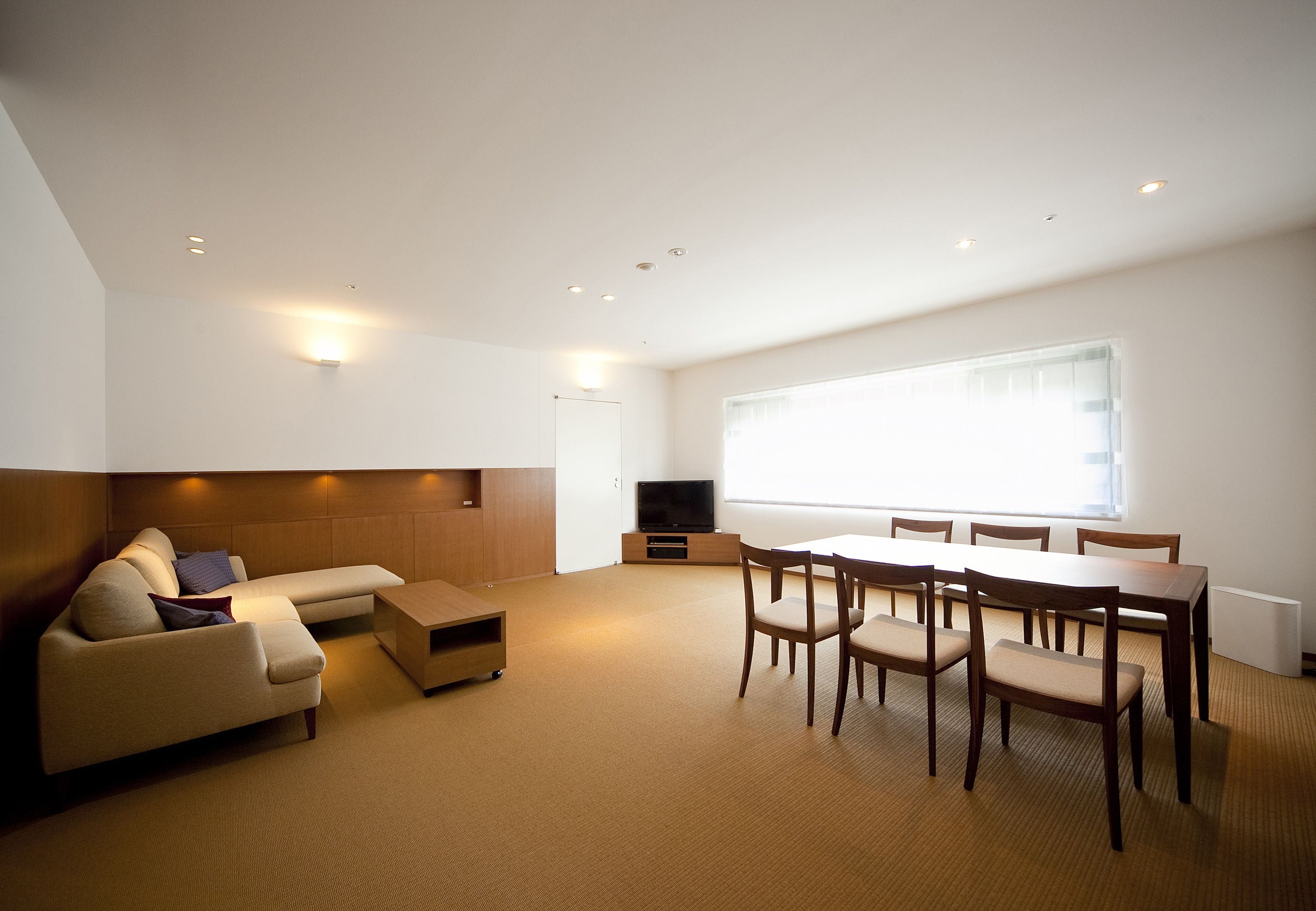 A modern living room with a sofa, coffee table, dining table, and chairs.